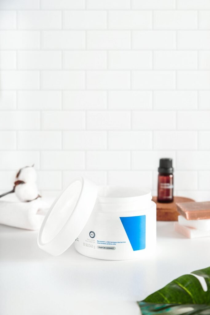 Open cosmetic cream jar on white background with natural decor.