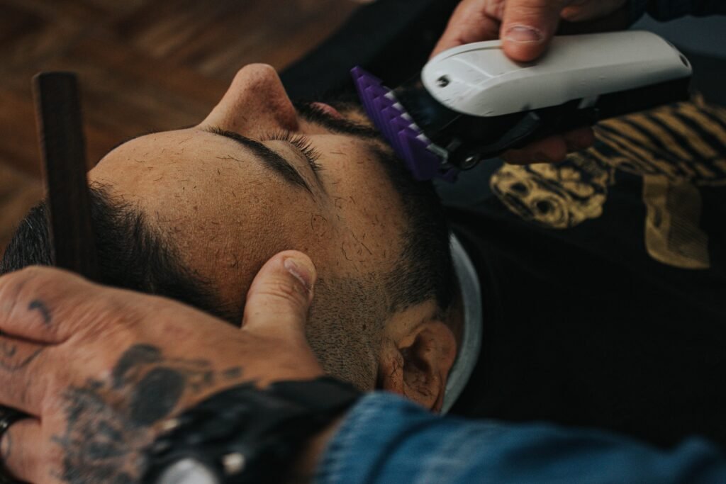 A barber skillfully shapes a beard with clippers, showcasing precision in men's grooming.