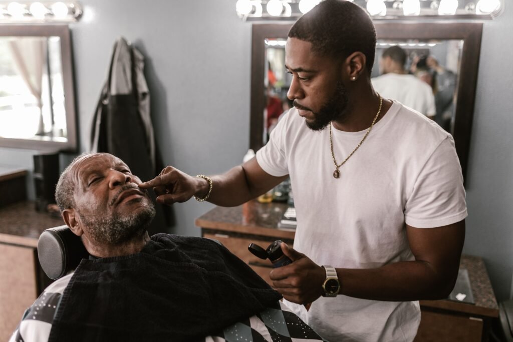 A barber expertly trims an elderly client's beard in a stylish barbershop.