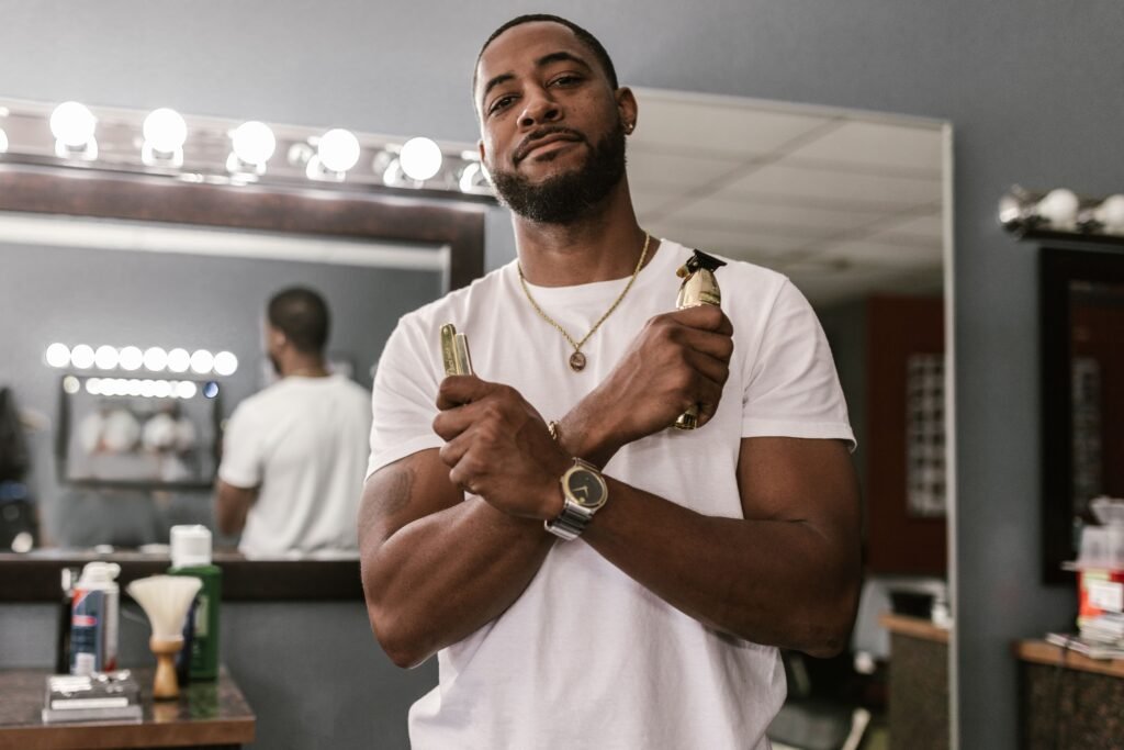 Barber in a stylish shop holding clippers with a confident pose, ready for work.