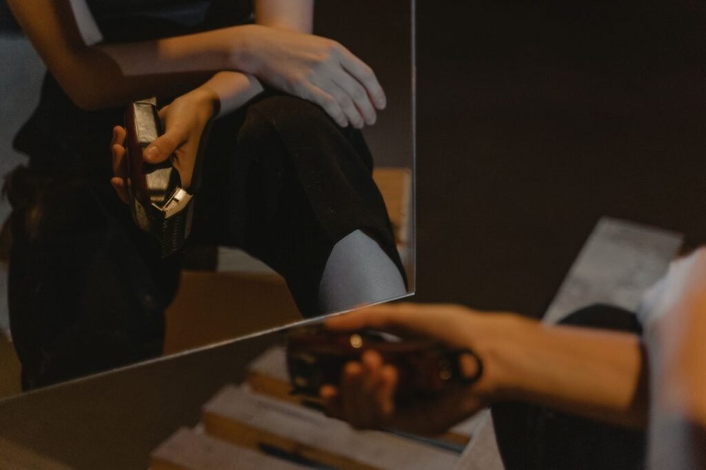 A person is reflected in the mirror holding an electric shaver indoors.